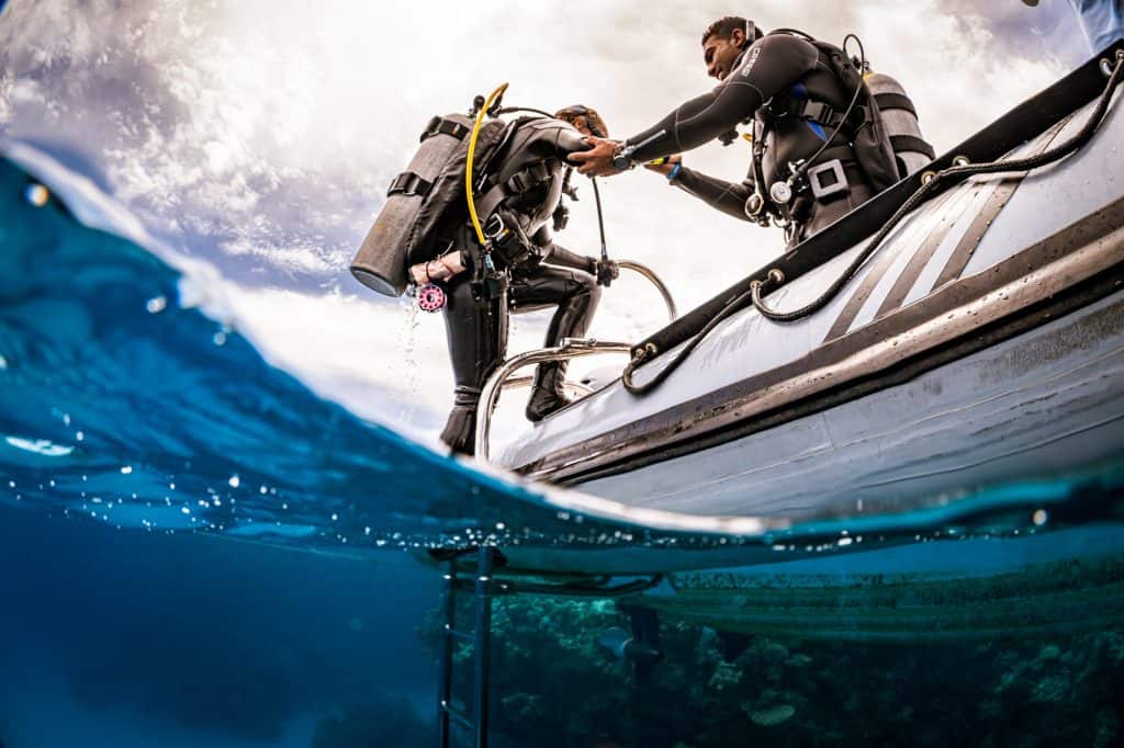 A diver being helped back aboard a RIB dive boat by a crew member