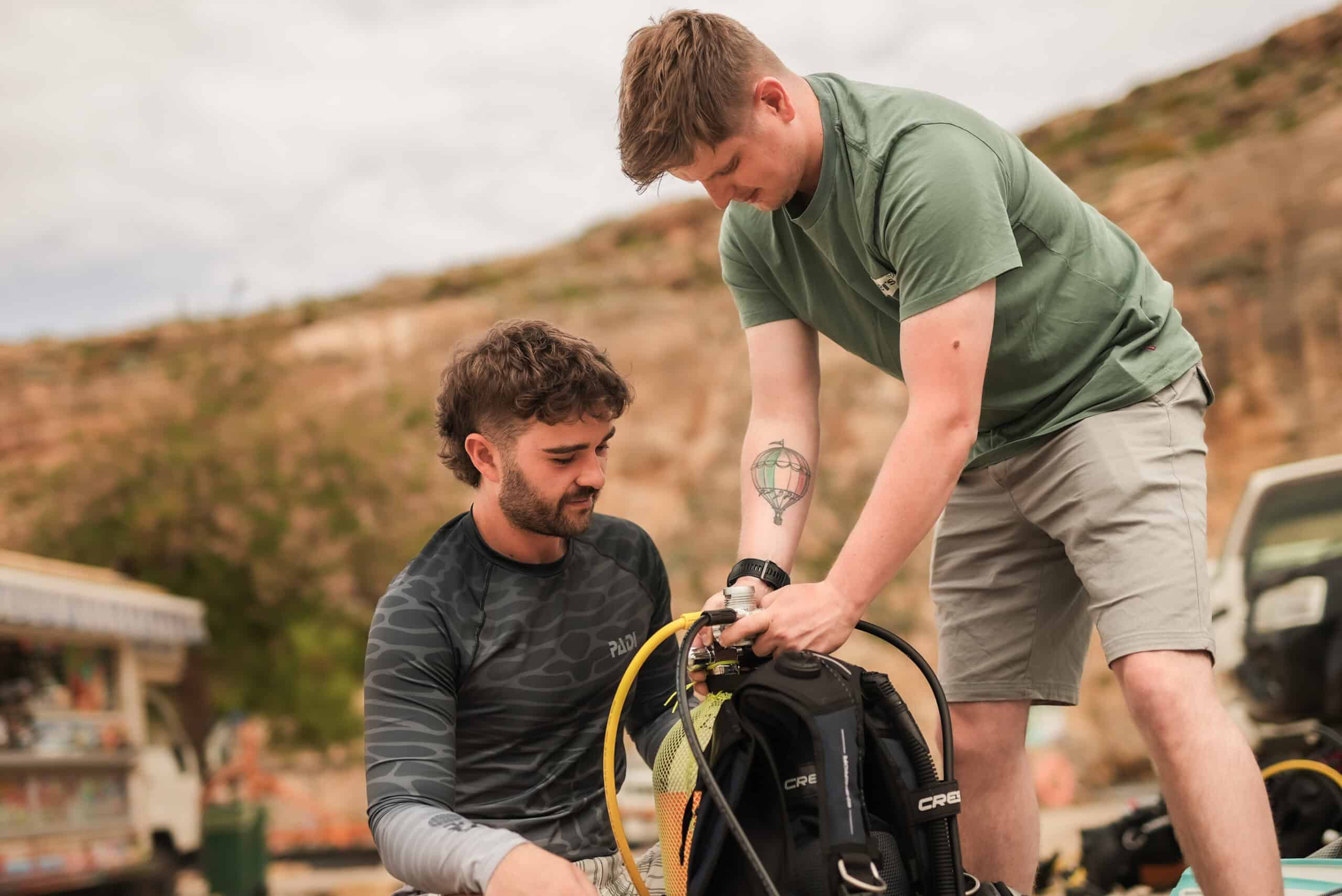 Two divers assembling a regulator onto a cylinder before a dive