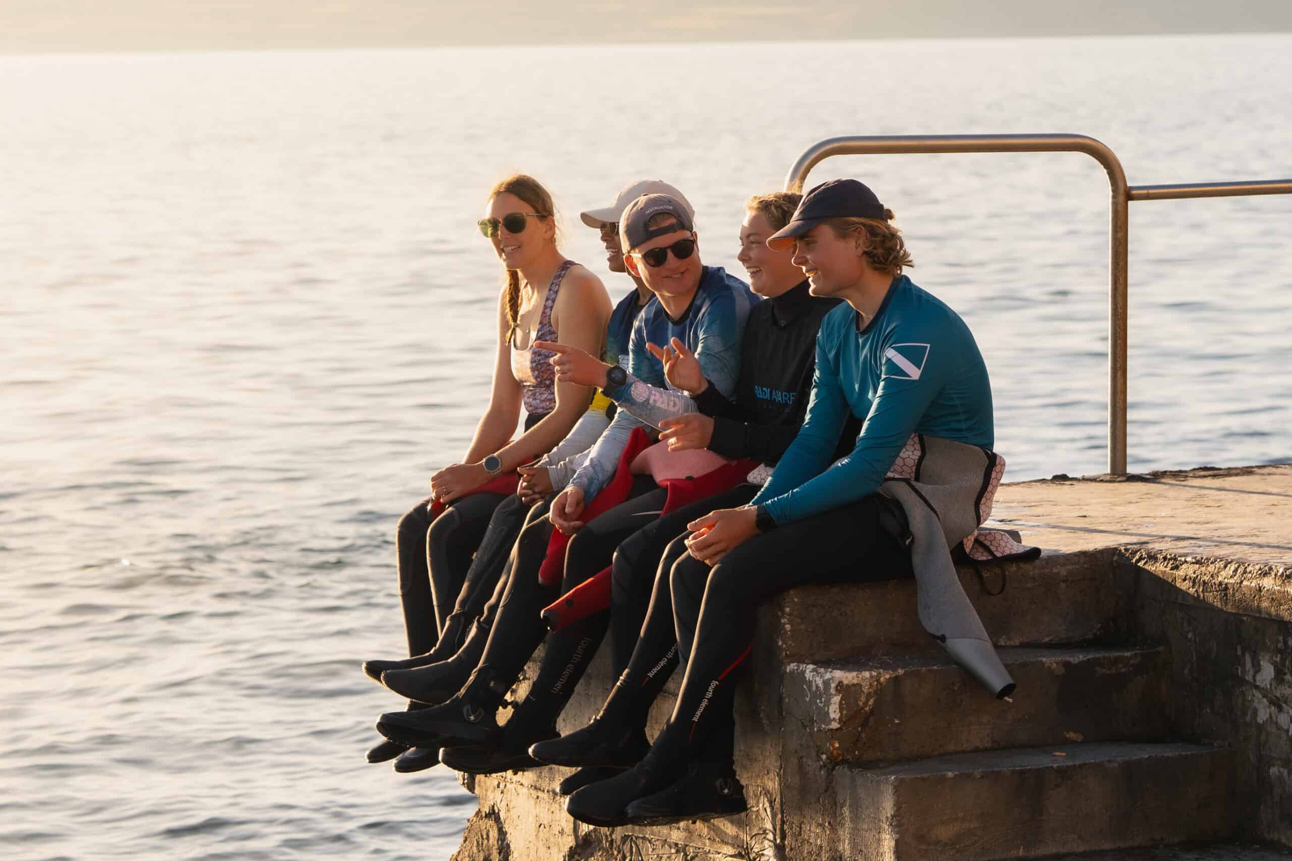 Club divers sitting together on a harbour wall at the end of a dive day